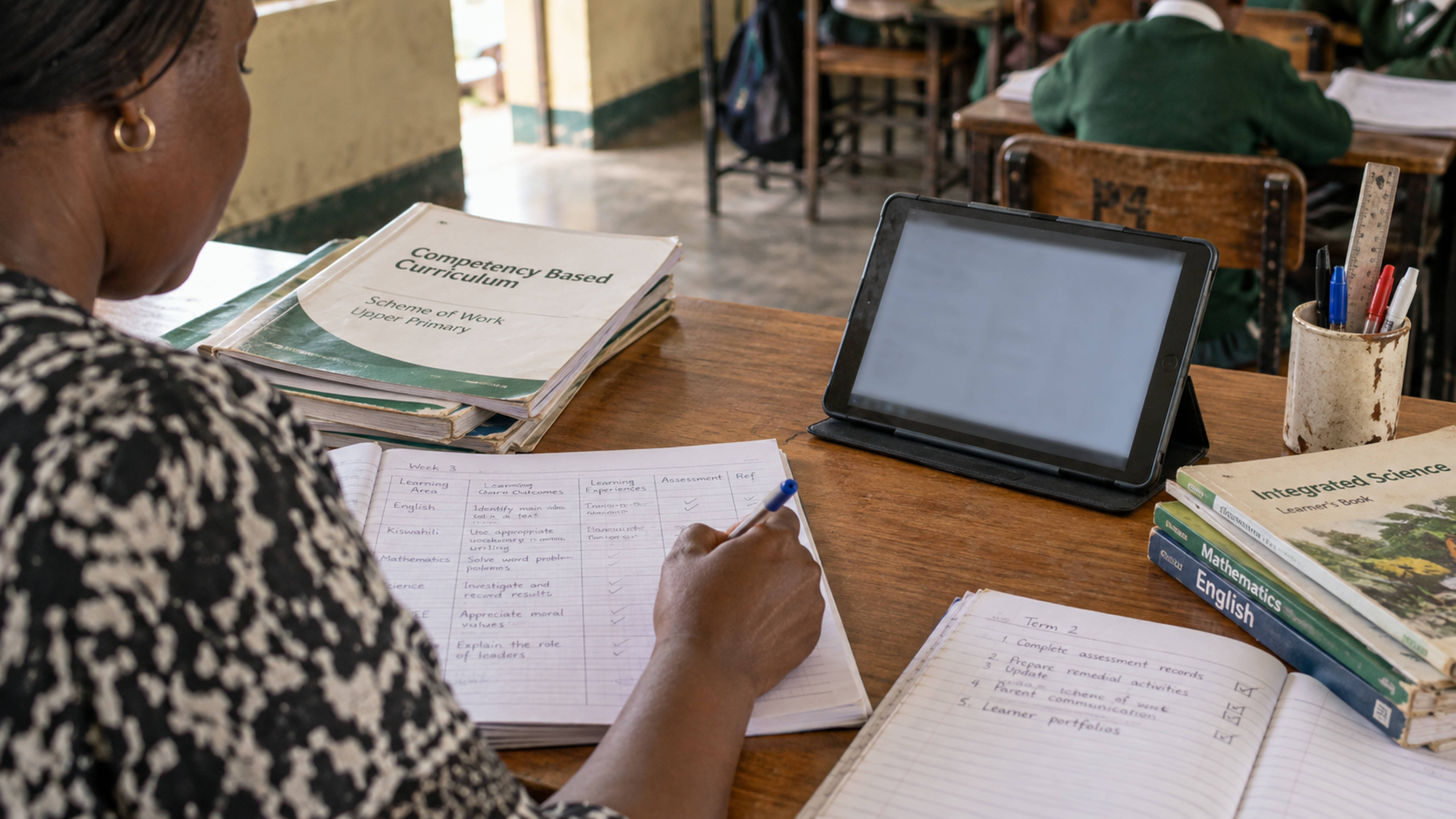 Printed CBC materials and a tablet on a teacher’s desk.
