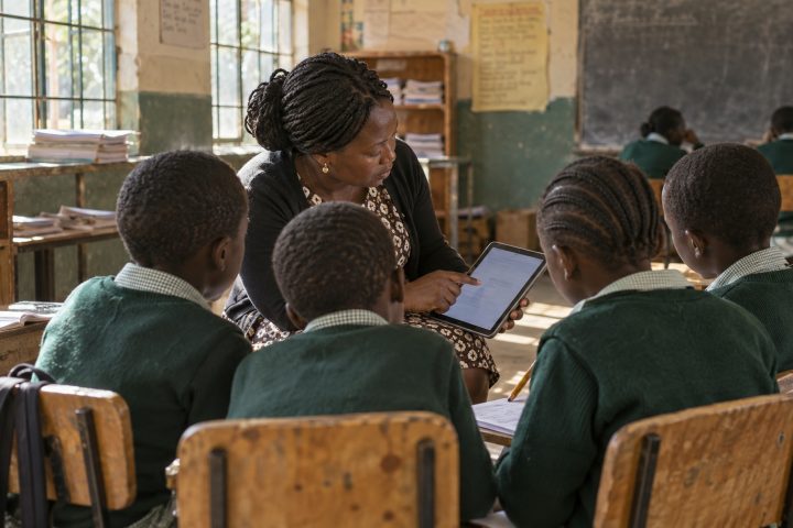 A teacher marks a small group against indicators on a tablet.
